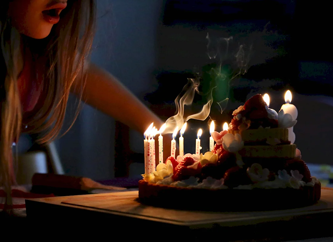 Задувает свечи на торте